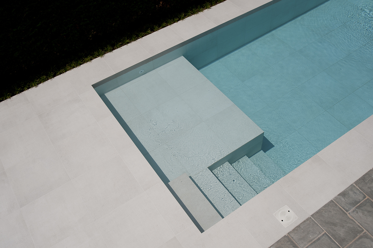 Piscina realizzata in grès porcellanato calce. Progetto di outdoor con piscina con focus sul colore bianco e la pulizia delle linee.